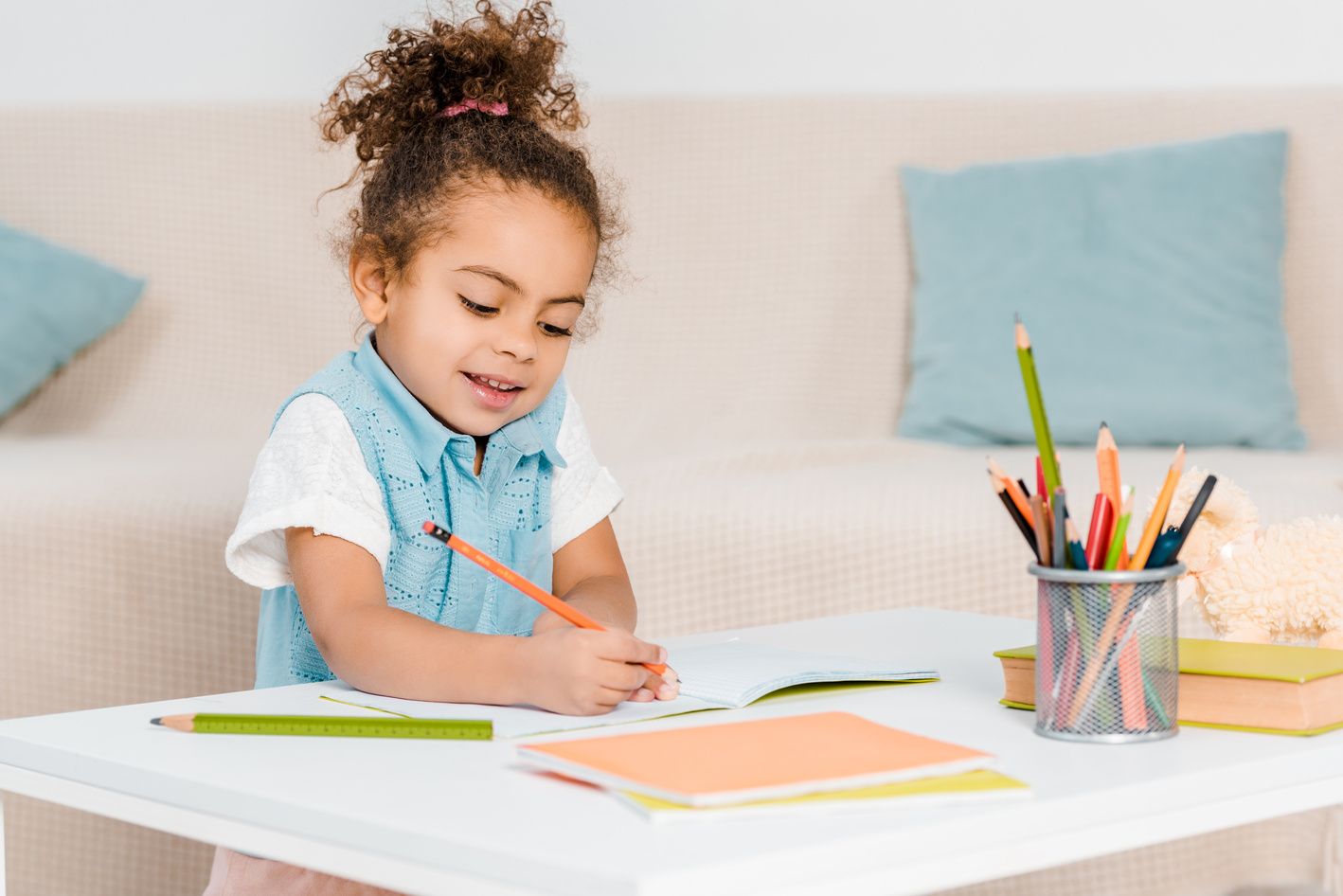 adorable smiling african american child studying and writing with pencil